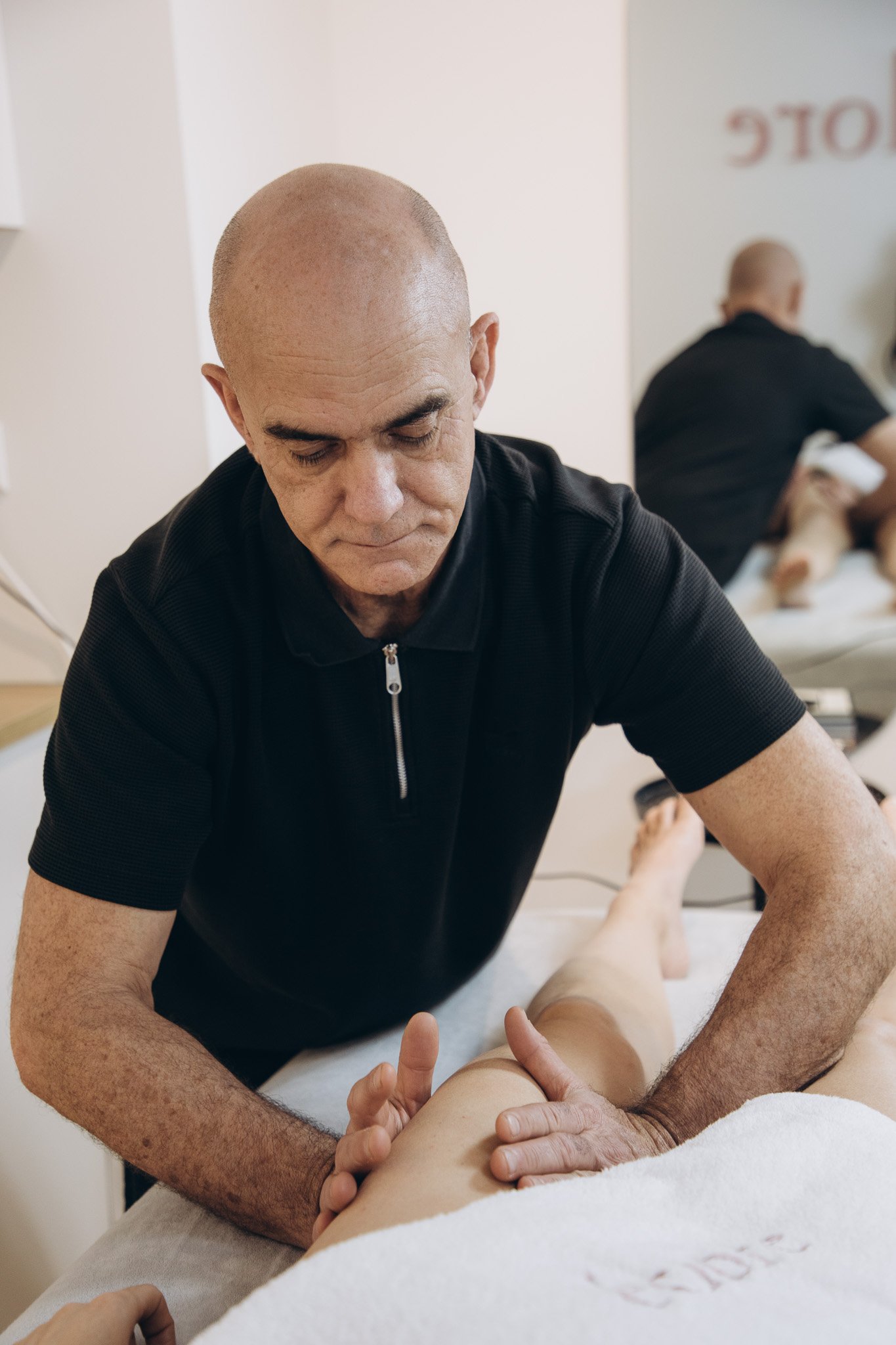 Alex Van De Bilt performing a manual remodelling massage on a client's leg in the Éclore Clinics treatment room in Utrecht